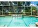 Screened in pool with a lovely waterfall feature and lush green foliage surrounding the enclosure at 1903 Curry Rd, Lutz, FL 33549