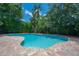 An inviting turquoise pool is surrounded by lush tropical greenery and a brick paver patio at 204 E North St, Tampa, FL 33604