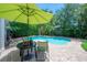 Relaxing pool with table, chairs, and umbrella, surrounded by lush greenery on a brick paver patio at 204 E North St, Tampa, FL 33604