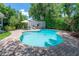 A freeform pool is surrounded by lush tropical greenery and a brick paver patio with a table and umbrella at 204 E North St, Tampa, FL 33604