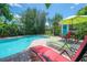 Outdoor pool area features lounge chairs, an umbrella, and lush greenery for a private backyard experience at 204 E North St, Tampa, FL 33604