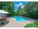 Relaxing pool with lounge chairs, table, and umbrella, surrounded by lush greenery on a brick paver patio at 204 E North St, Tampa, FL 33604