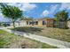 Cozy home with an attached garage, lovely landscaping, and a walkway to the front door with sunny sky at 2632 Tung Dr, Holiday, FL 34691
