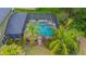 Aerial view of a screened pool area with a freeform pool, spa, and lush tropical landscaping at 2712 Spring Meadow Dr, Plant City, FL 33566