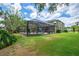 A backyard scene with a covered pool and green exterior of home surrounded by trees at 2712 Spring Meadow Dr, Plant City, FL 33566