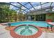 Inviting in-ground pool and spa within a screened enclosure, surrounded by green landscaping at 2712 Spring Meadow Dr, Plant City, FL 33566