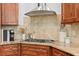 Close-up view of kitchen features stainless steel vent hood, gas cooktop, granite countertops, and mosaic tile backsplash at 2936 W Knights Ave # A, Tampa, FL 33611