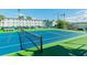 Outdoor tennis court with blue and green surface, net, and adjacent building with parking at 2960 59Th S St # 614, Gulfport, FL 33707