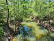 A tranquil creek with tree-lined banks, reflecting the sky and surrounding nature at 35031 Shale St, Webster, FL 33597