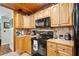 Kitchen is adorned with honey colored wood cabinetry, black appliances, and tile backsplash at 35031 Shale St, Webster, FL 33597