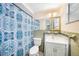 Functional bathroom with patterned shower curtain, toilet, mirror, and vanity with a sink at 4312 Las Vegas Dr, New Port Richey, FL 34653