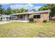 Single-story home with stone exterior details and a screened porch, complemented by lush surrounding trees at 4312 Las Vegas Dr, New Port Richey, FL 34653