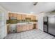 Spacious kitchen featuring tile flooring, wooden cabinets, stainless steel refrigerator, and outdated countertops at 4312 Las Vegas Dr, New Port Richey, FL 34653