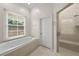 Bright bathroom featuring a soaking tub under a window and glass door shower at 4518 W Woodmere Rd, Tampa, FL 33609