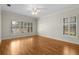 Bedroom featuring hardwood floors, large windows, white trim, and a ceiling fan for comfort at 4518 W Woodmere Rd, Tampa, FL 33609
