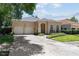 Charming home featuring a two-car garage, brick driveway, manicured landscaping, and a welcoming entrance at 4518 W Woodmere Rd, Tampa, FL 33609