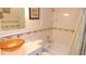 A bathroom featuring a clear sink, white walls with decorative tiles and a shower and bathtub combo at 4744 Azalea Dr # 203B, New Port Richey, FL 34652