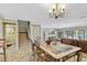 Open dining area featuring tiled floors, glass table, chandelier, and staircase access for easy movement at 511 Sandy Hook Rd, Treasure Island, FL 33706