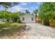Rear view of the home showing white siding, and a parking area with gravel at 670 Wooddell Dr, Safety Harbor, FL 34695