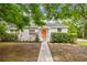 Charming single-story home featuring a neatly landscaped yard, a bright coral-colored front door, and mature shade trees at 670 Wooddell Dr, Safety Harbor, FL 34695