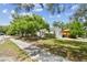 Lovely landscaped yard with green grass, mature trees, and white siding at 670 Wooddell Dr, Safety Harbor, FL 34695