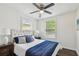 Comfortable main bedroom with a tufted headboard, plush bedding, hardwood floors, and natural light from two windows at 670 Wooddell Dr, Safety Harbor, FL 34695