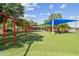 Community playground with swings, climbing structures, and a blue shade canopy at 670 Wooddell Dr, Safety Harbor, FL 34695