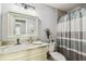 Well-lit bathroom featuring a decorative mirror, marble countertop, and tiled shower at 7004 Westminster St, Tampa, FL 33635