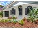 Charming home exterior with lush landscaping, updated dark windows and a quaint front door at 7208 S Juanita St, Tampa, FL 33616