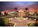 Connerton clubhouse exterior at sunset featuring a fountain, palm trees, and beautiful landscaping at 7754 Painted Sky Pl, Land O Lakes, FL 34637