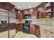 A kitchen featuring stainless steel refrigerator and dark wood cabinetry, complimented by granite countertops at 8001 Pagoda Dr, Spring Hill, FL 34606