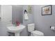 Cozy half bathroom with a pedestal sink, toilet, mirror, and neutral gray walls at 8007 Bally Money Rd, Tampa, FL 33610