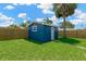 Backyard shed for extra storage with lush green grass, mature trees, and a fenced perimeter at 8314 Stillbrook Ave, Tampa, FL 33615