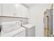 A well-lit laundry room features a washer, dryer, and white cabinets for storage at 842 Tennyson Mill Cir, Tampa, FL 33619