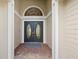 Elegant double front doors with decorative glass inserts, enhanced by an arched window and brick flooring at 9084 Quail Creek Dr, Tampa, FL 33647