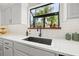 Stylish kitchen sink featuring white countertop, white cabinets, and large window with natural light at 9084 Quail Creek Dr, Tampa, FL 33647