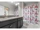 Bathroom featuring dual granite vanity, framed mirror, and shower with 'Paris' themed curtain at 9931 Victory Gallop Loop, Ruskin, FL 33573