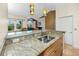 Kitchen island with stainless steel sink, granite countertops, wooden cabinets and colorful pendant lights at 10764 70Th Ave # 5302, Seminole, FL 33772