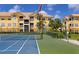 Well-maintained tennis court with a net in front of a yellow condo building under a partly cloudy sky at 10764 70Th Ave # 5302, Seminole, FL 33772