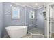 Modern bathroom featuring luxurious soaking tub and glass enclosed shower with blue tiled walls at 1171 Red Maple Ne Cir, St Petersburg, FL 33703