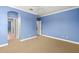 Bright bedroom featuring neutral carpet, ceiling fan, blue walls, and open doorways at 1171 Red Maple Ne Cir, St Petersburg, FL 33703