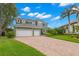 Two-story green home featuring a three-car garage and long paved driveway and manicured front lawn at 1171 Red Maple Ne Cir, St Petersburg, FL 33703