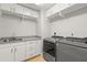 Well-lit laundry room features stainless steel sink, gray countertops, white cabinets, and modern gray washer and dryer at 1171 Red Maple Ne Cir, St Petersburg, FL 33703