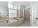 This bathroom features a bathtub, walk-in shower, tiled floor, and a window for natural light at 12339 Roseland Dr, New Port Richey, FL 34654