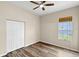 This bedroom features hardwood floors, a ceiling fan, a window for natural light, and a closet at 12339 Roseland Dr, New Port Richey, FL 34654