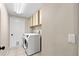 Functional laundry room featuring modern appliances, overhead cabinets and tile flooring at 12339 Roseland Dr, New Port Richey, FL 34654