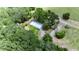 Aerial view of rural home with metal roof nestled among lush trees and green spaces at 12434 Cody Dr, Wimauma, FL 33598