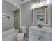 Modern bathroom features gray tiled shower/tub combo, white vanity, and a contemporary mirror at 12434 Cody Dr, Wimauma, FL 33598