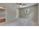 This spacious bedroom features neutral carpet, a ceiling fan, and natural light from the window at 12434 Cody Dr, Wimauma, FL 33598