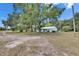 Exterior view of a home surrounded by trees and open space, with a circular driveway at 12434 Cody Dr, Wimauma, FL 33598